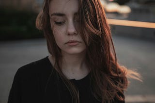 Teenage girl with long, brown hair looking sad