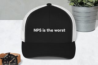Um boné com as laterais na cor branca e a frente na cor preta preta, com a seguinte frase escrita em branco: NPS is the worst.