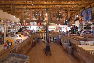 Interior of a trading post in Arizona, with wooden floor and ceiling with various Indigenous artifacts on the walls.