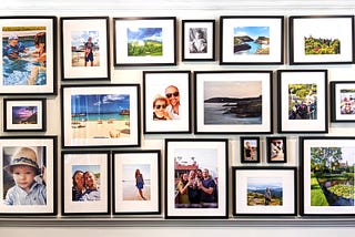 A gallery wall of framed photos, including  landscapes and family portraits.