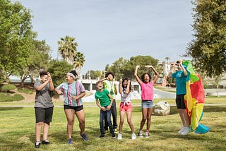 diverse group of kids laughing together in sunny, grassy park