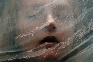 A person’s face behind a sheet of plastic.