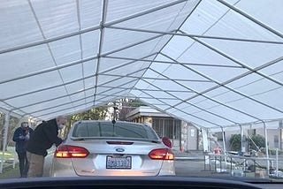 The tent from my car window showing the car in front of me getting the vaccine.