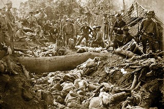 Image of the massacre of Bud Dajo, Jolo Island, Philippines with US soldiers posing beside a mass grave of decaying victims.