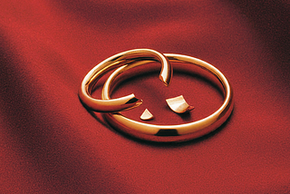 Two wedding bands, one broken, on a background of red fabric