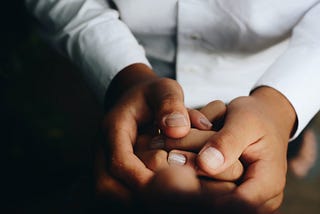 A pair of hands is held in by another pair of hands