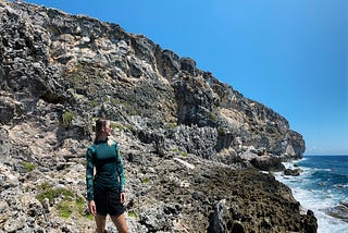 picture of a woman in front of a cliff beside the ocean