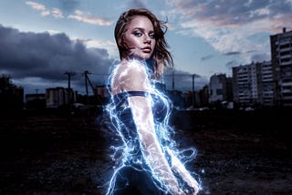 A woman superhero with dark hair sweeping in the wind, electricity crackling around her, looking over her shoulder into the camera. In the background is a dark cityscape.