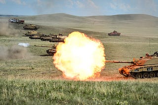 9 Beige desert camouflage Challenger 2s in a firing line devastaing targets with their main 120mm guns.