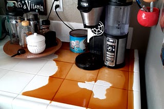 My real-life coffeemaker  without a carafe, coffee spilled widely over the countertop.