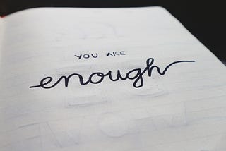 A page in a book displaying the phrase “You are enough” in black letters against a white background.