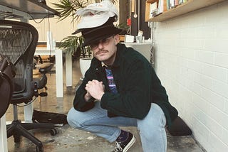 Man with many hats on his head, while in a prayer squatting position