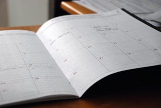 A monthly calendar in a notebook. A few entries are added to a few days