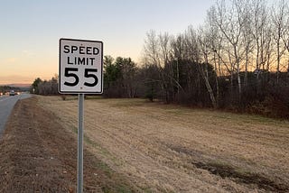 55 mph speed limit sign along a highway in late autumn
