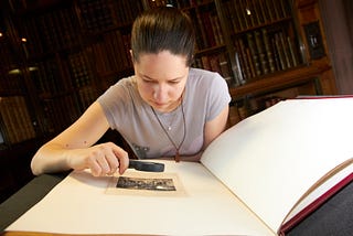 Woman examining old photography using magnifying glass