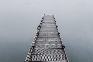 An image of a pier leading into the fog.