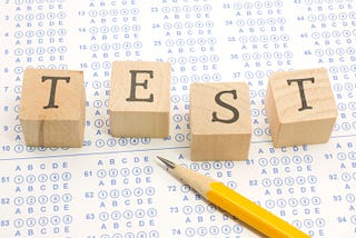 A pencil and T-E-S-T spelled out in letter cubes on top of a test bubble sheet