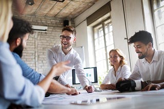 A group of business people sit around, satisified with their employment. How? They followed Acorn Labs extensive of guide on measuring and improving employee satsifaction.