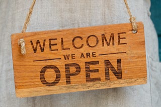 wood sign with written text on it: welcome — we are open.