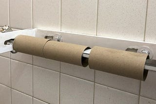 Three empty toilet paper rolls in a rest stop bathroom.