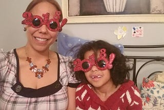 Mother and daughter wearing festive, glitter-crusted 2018 sunglasses for New Year’s Eve.