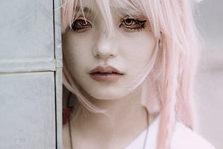 Young woman with pink hair and creative makeup, looking sad