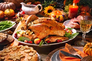 A Thanksgiving buffet table, with Turkey, sliced ham, pie, gravy, greenbeans, decorated with wild flowers, candles and squash