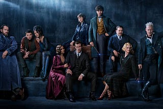 The cast of Fantastic Beasts 2 dressed as their characters in front of a blue dark background.