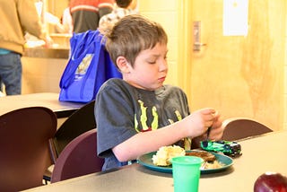 Boy at a shelter eating a meal.