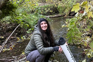 A smiling young woman in a creek bed doing a survey for mussels