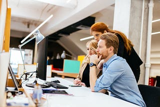 A harmonious team of three is focused on something in front of a PC