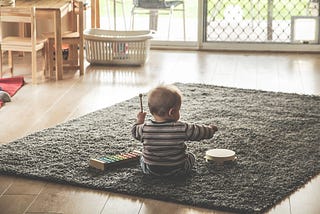 Baby learning about music by playing with a tambourine and a xylophone