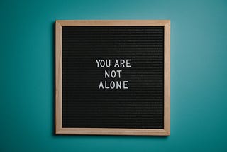 small black chalkboard with “you are not alone” in white letters.