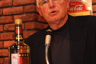 A gentleman wearing a suit and talking at the podium