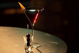 An enticing image of a Manhattan cocktail in an elegant glass with an orange twist and 3 cherries