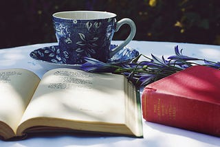 Poetry book on table with tea, flowers, and other books.