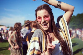 Young woman in pink sunglasses poses for the camera at a music festival