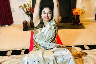 Author in a saree, seated on her mat cross-legged practicing mountain pose.