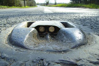 Photo of a Catseye set into a road, with the rubber housing and the glass reflectors visible