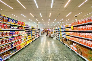 Aisle of a grocery store with only one person in the far distance