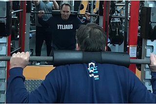 A software engineer lifting weights, wearing a sweatshirt with “QUALITY” written on the front.