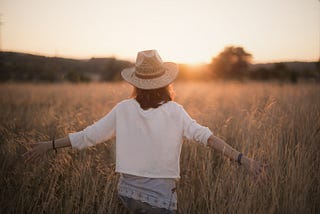 Woman alone in field at sunrise / sunset