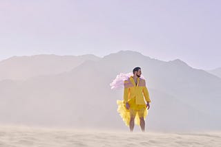 Young man in fashionable, yellow outfit standing in desert