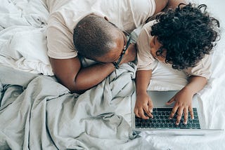 Black father working from home with child on laptop