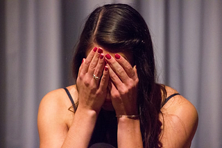 A woman with her hands covering her face.