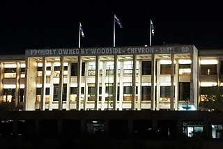 West Australia’s parliament house with the words “Proudly Owned by Woodside — Chevron — Shell — BP” projected directly onto it.