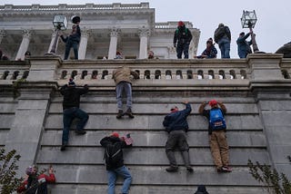 Insurrectionists climbing the walls of the Capitol on 1/6/21