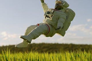 An astronaut floats over a plane of grass.