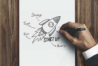Man drawing a rocket ship labeled ‘Start up’