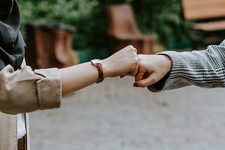 two people meet on the street and put their fists together instead of handshake